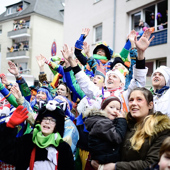 Verkleidete Menschen stehen am Rand eines Karnevalszugs