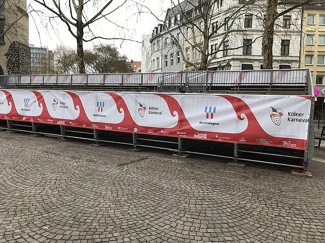 Tribüne ohne Dach am Zugwegrand mit Werbebannern.